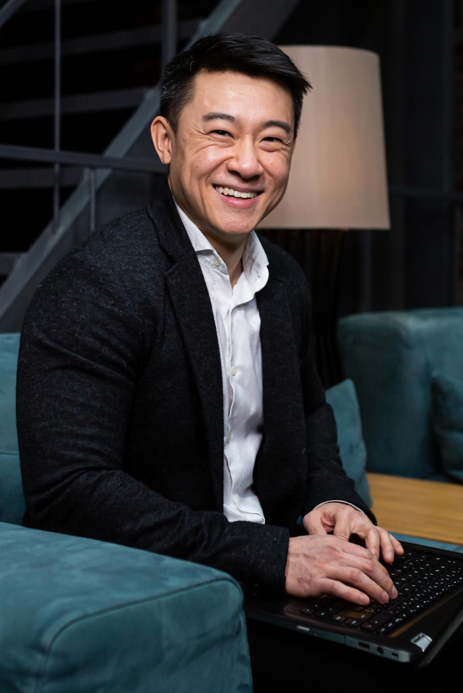 A smiling man works on a laptop computer